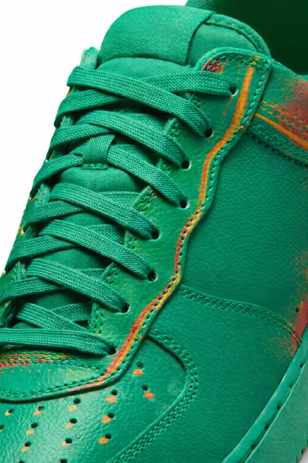 Close-up of a green sneaker with orange accents on a white background
