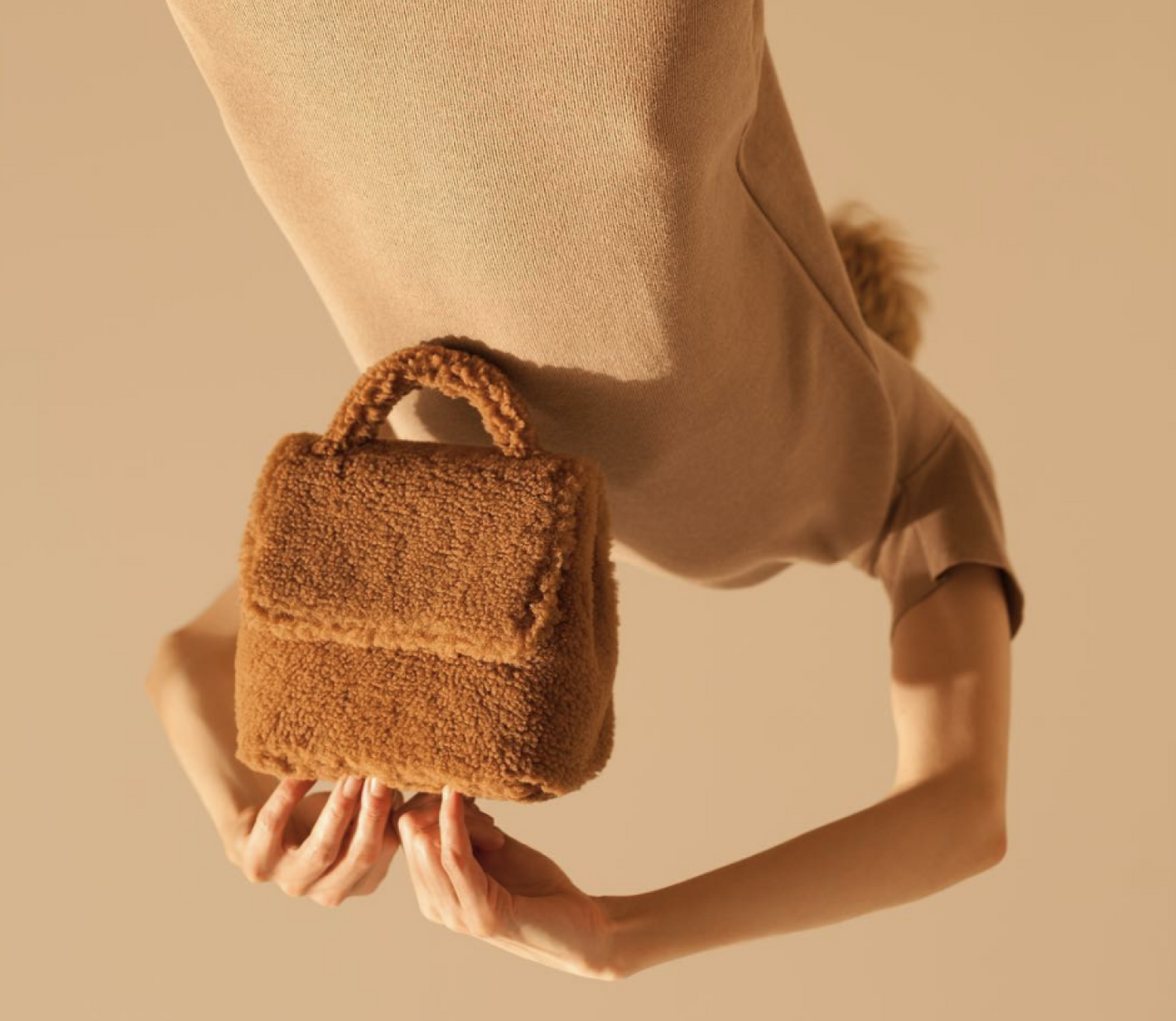 A woman holding a fuzzy brown handbag. 