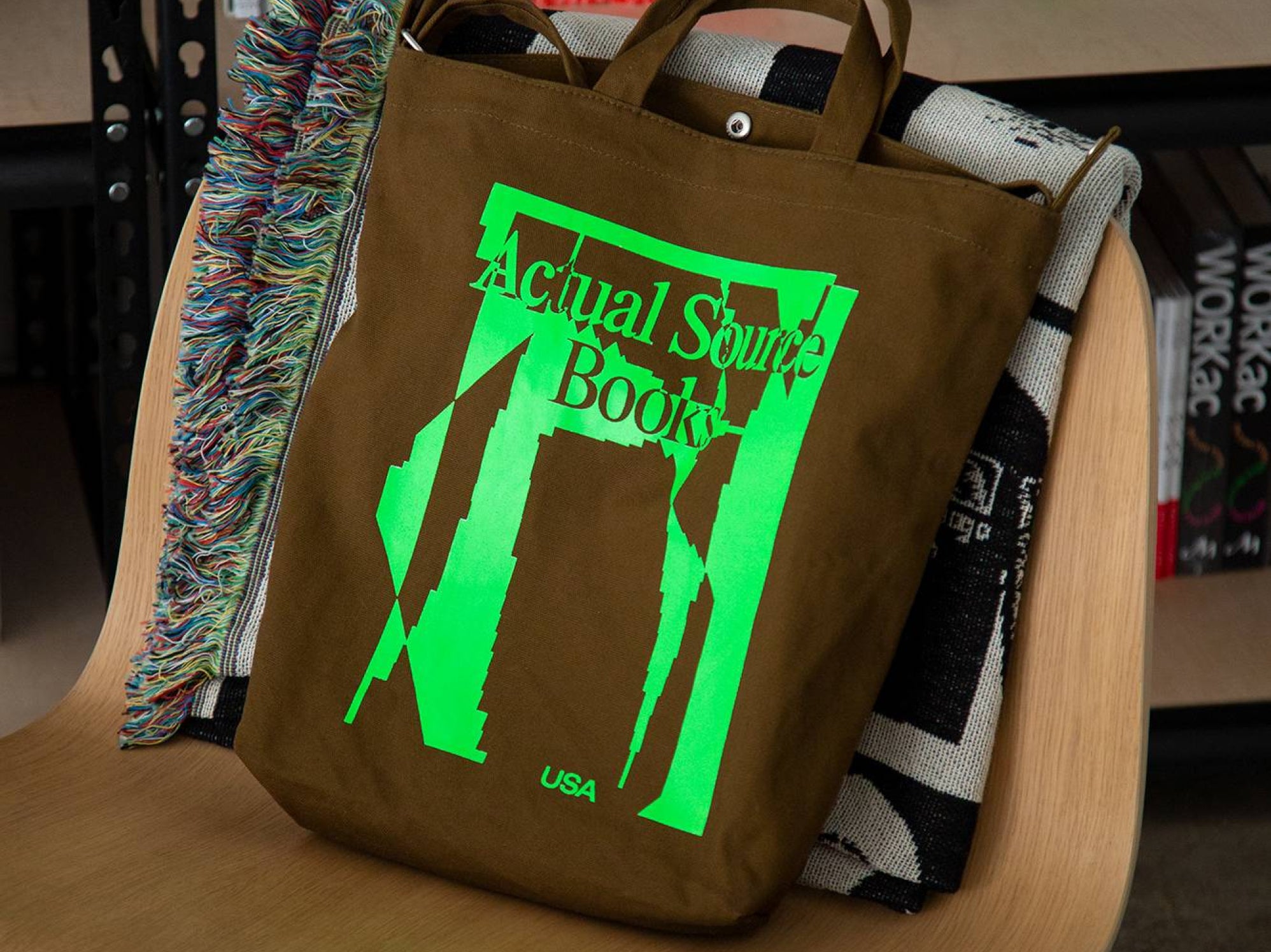 A brown and lime green tote bag sits on a wooden chair. 